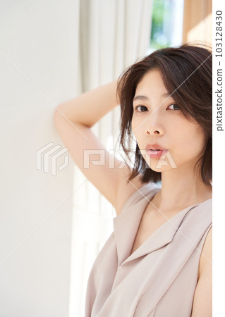 Young woman basking in the sun by the window Young woman basking in the sun by the window 103128430