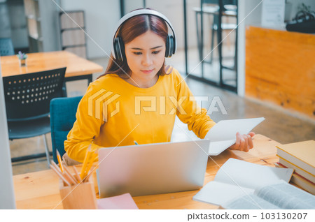 young student wearing headphones studies online, distance learning, and keeps up to date on the global coronavirus pandemic. 103130207