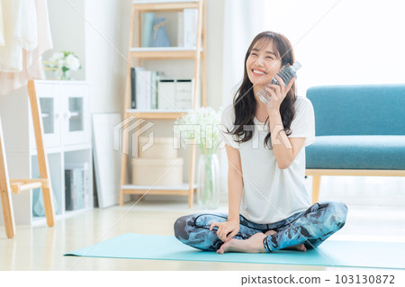 Young woman taking a break by drinking mineral water while doing yoga Young woman taking a break by drinking mineral water while doing yoga 103130872