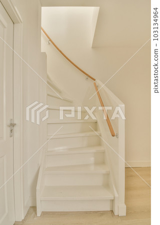 an empty room with stairs in the middle and light wood floors on the bottom, white walls and wooden handrails 103134964