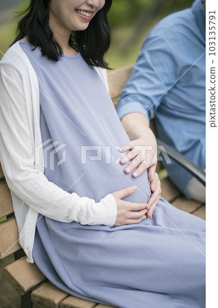 A pregnant woman and her husband resting in the park 103135791