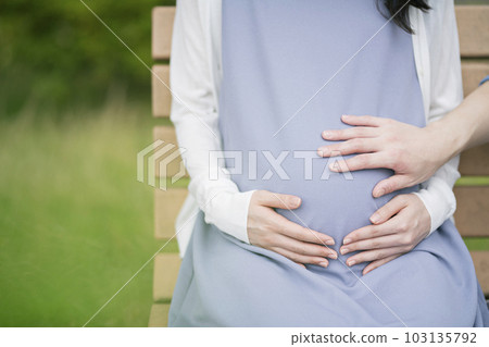 A pregnant woman and her husband resting in the park 103135792
