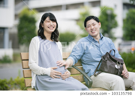 A pregnant woman and her husband resting in the park A pregnant woman and her husband resting in the park 103135798