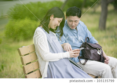 Young couple looking at smartphone in the park Young couple looking at smartphone in the park 103135799