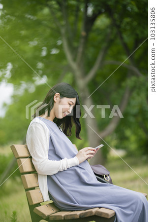 孕婦在公園裡看智能手機 孕婦在公園裡看智能手機 103135806
