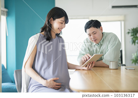 Young couple looking at a tablet together in the living room 103136317