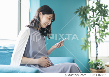 pregnant woman looking at smartphone 103136333