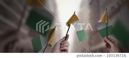 A group of people holding small flags of the Cote dIvoire in their hands A group of people holding small flags of the Cote dIvoire in their hands 103136716