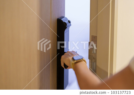 Hand using smart digital door lock while open or close the door at home or apartment. NFC Technology, Fingerprint scan, keycard, PIN number, smartphone, electrical and contactless lifestyle concepts 103137723