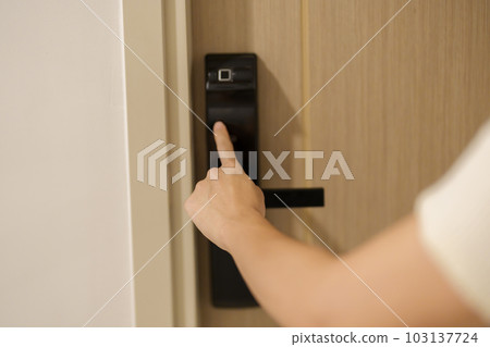 Hand press PIN number for smart digital door lock while open or close the door at home or apartment. NFC Technology, Fingerprint scan, keycard, smartphone and contactless lifestyle concepts 103137724
