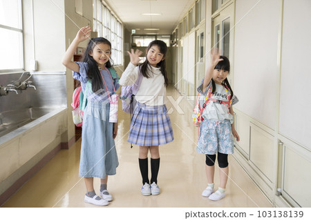 Girl waving in school corridor 103138139