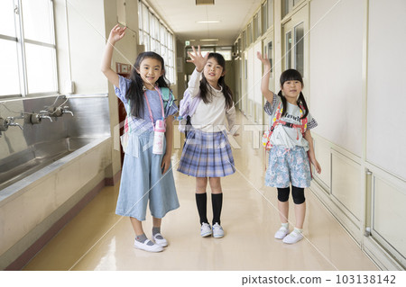 Girl waving in school corridor Girl waving in school corridor 103138142