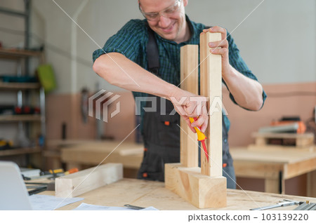 Caucasian man assembling a table with a screwdriver.  103139220