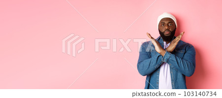 Serious african-american man saying no, showing cross to stop something bad, prohibit action, standing over pink background Serious african-american man saying no, showing cross to stop something bad, prohibit action, standing over pink background 103140734