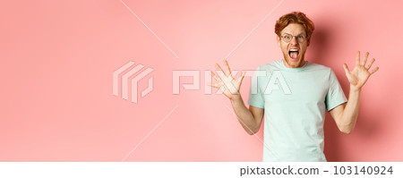 Angry and pressured young man losing temper, spread hands sideways and screaming with furious face, standing in glasses and t-shirt against pink background Angry and pressured young man losing temper, spread hands sideways and screaming with furious face, standing in glasses and t-shirt against pink background 103140924