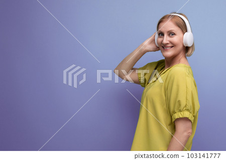 portrait of blond mature yo woman in big headphones on studio background with copy space portrait of blond mature yo woman in big headphones on studio background with copy space 103141777