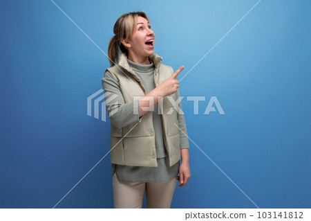 blond surprised joyful young woman points with hand at interesting news 103141812