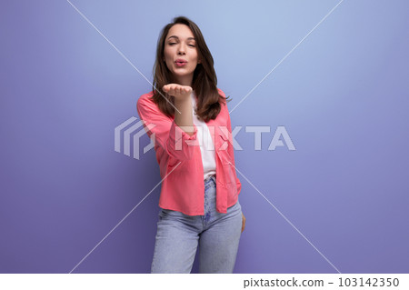 portrait of a dreamy young woman with dark brown hair in jeans blowing a kiss portrait of a dreamy young woman with dark brown hair in jeans blowing a kiss 103142350