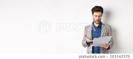 Confused businessman looking at bad document, complaining on deal, pointing at paper frustrated, standing in suit on white background 103142570