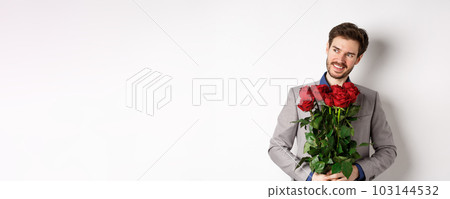 Charming smiling man going on romantic date, wearing suit, holding bouquet of roses and looking left, standing on valentines day with gift on white background Charming smiling man going on romantic date, wearing suit, holding bouquet of roses and looking left, standing on valentines day with gift on white background 103144532