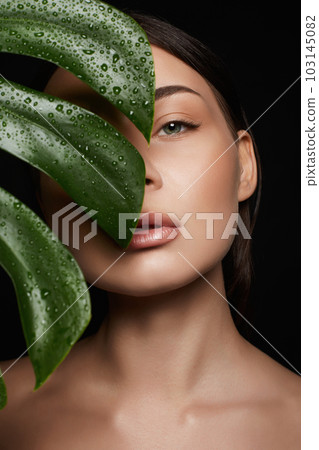 Beauty Portrait of brunette girl in palm leaves. Beautiful young woman with Make-up Beauty Portrait of brunette girl in palm leaves. Beautiful young woman with Make-up 103145082