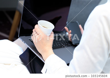 坐在床上喝咖啡並使用智能手機和電腦的女人 103145604