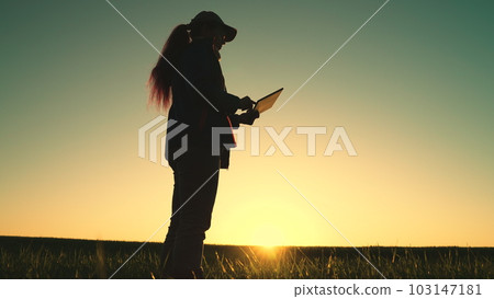 woman farmer agronomist walks through wheat field working with digital tablet. farming. griculture. harvesting.peasant girl walks along road along wheat fields carries digital tablet her hand. smart woman farmer agronomist walks through wheat field working with digital tablet. farming. griculture. harvesting.peasant girl walks along road along wheat fields carries digital tablet her hand. smart 103147181