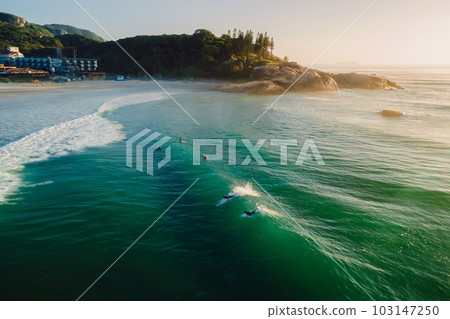 Sunrise on ocean with surfers on wave. Joaquina beach in Brazil 103147250
