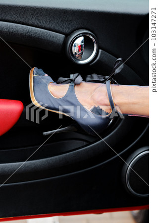 Closeup of slender female leg in vintage stockings and shoe rest against the car door 103147271