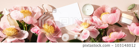 Top view of natural cosmetics and pink peonies on pastel blue background with white card for invitation, logo or design 103148012