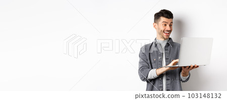 Man watching funny video on laptop, laughing at computer screen and smiling joyful, standing on white background Man watching funny video on laptop, laughing at computer screen and smiling joyful, standing on white background 103148132