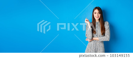 Beautiful caucasian woman 25s wearing dress, standing against blue background and smiling confident 103149155