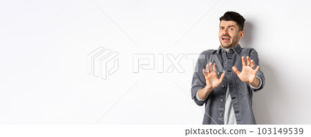 Stay away from me. Scared young man screaming and asking to stop, step back and look frightened, rejecting something bad, standing on white background 103149539