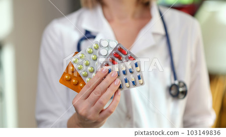Nutritionist holds fan of different pills in hand in clinic 103149836