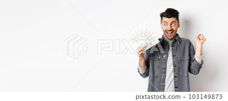 Lucky man winning prize money and scream of excitement, staring at dollar bills happy, standing on white background 103149873