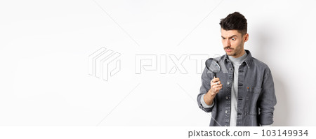 Serious man investigating, looking down with magnifying glass, stare serious, standing on white background Serious man investigating, looking down with magnifying glass, stare serious, standing on white background 103149934