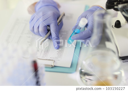 Scientist compares results of research to data in paper Scientist compares results of research to data in paper 103150227