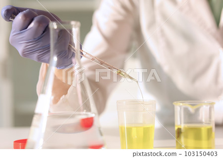Laboratory worker pours urine into test tube using pipette 103150403