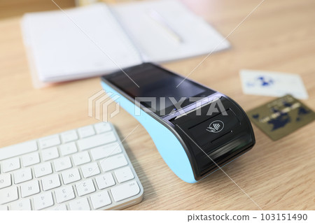 Portable terminal and bank credit cards lie on wooden table 103151490