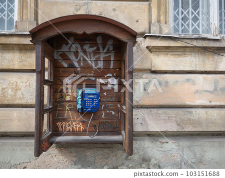 [Ukraine] A blue retro pay phone with graffiti attached to the outer wall of the old town of Lviv 103151688