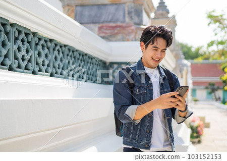 Portrait of Asian male traveler using a mobile phone on sidewalk of buddhist temple on street in Bangkok, Thailand, Southeast Asia - smart phone and internet for traveling concept Portrait of Asian male traveler using a mobile phone on sidewalk of buddhist temple on street in Bangkok, Thailand, Southeast Asia - smart phone and internet for traveling concept 103152153