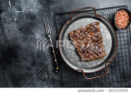 Alternative choice steak - Grilled Skirt or Machete beef meat. Black background. Top view. Copy space 103152503