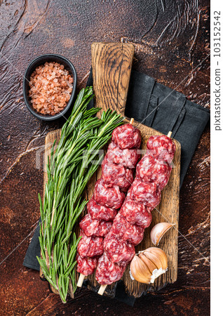 Raw traditional shish kebab Skewers with beef meat ans spices. Dark background. Top view 103152542
