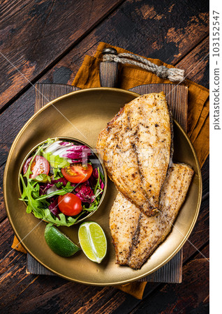 Roasted Gilthead Sea Bream fillets served with fresh vegetable salad. Wooden background. Top view 103152547