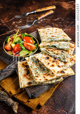 Freshly baked Turkish Gozleme, flatbread with greens and cheese. Dark background. Top view 103152557