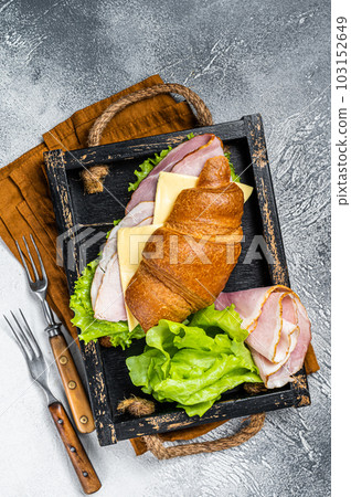 Fresh croissant sandwich with ham, cheese and salad leaf. Gray background. Top view Fresh croissant sandwich with ham, cheese and salad leaf. Gray background. Top view 103152649