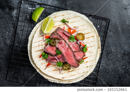 Grilled Beef steak Fajitas, taco tortillas with onion, jalapeno and bell pepper. Black background. top view Grilled Beef steak Fajitas, taco tortillas with onion, jalapeno and bell pepper. Black background. top view 103152661