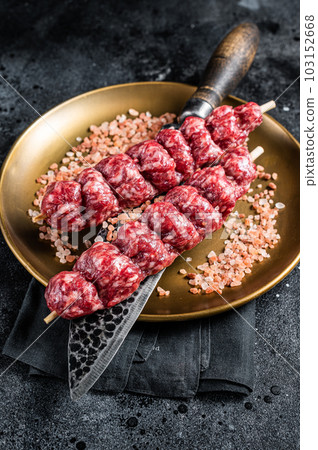 Raw kofta, kofte kebab Skewers with beef and lamb meat and spices. Black background. Top view Raw kofta, kofte kebab Skewers with beef and lamb meat and spices. Black background. Top view 103152668