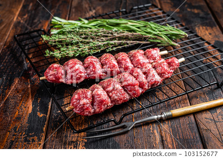 Raw kofta, kofte kebab Skewers with beef and lamb meat and spices ready for cooking. Wooden background. Top view Raw kofta, kofte kebab Skewers with beef and lamb meat and spices ready for cooking. Wooden background. Top view 103152677