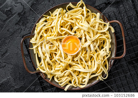 Dry spaetzle egg noodle in a steel tray. Black background. Top view 103152686
